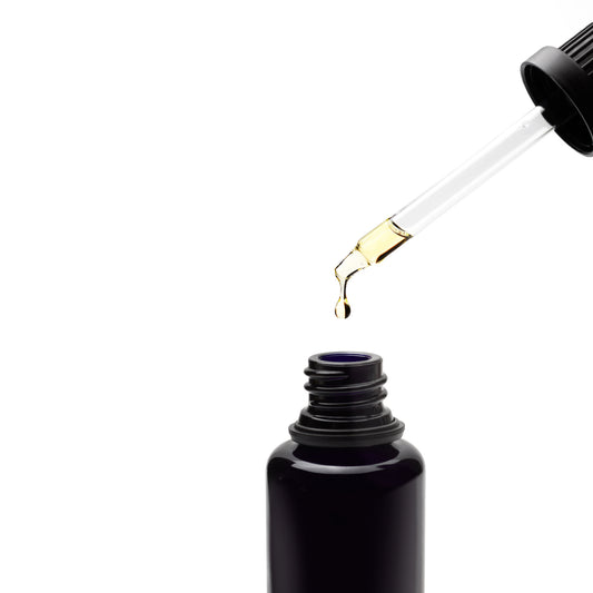 showing oil dripping into Black glass bottle with top in white background Hinoki Noir Red