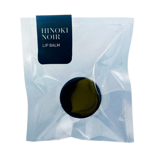 Hinoki Noir lip balm in a clear packaging on a white background