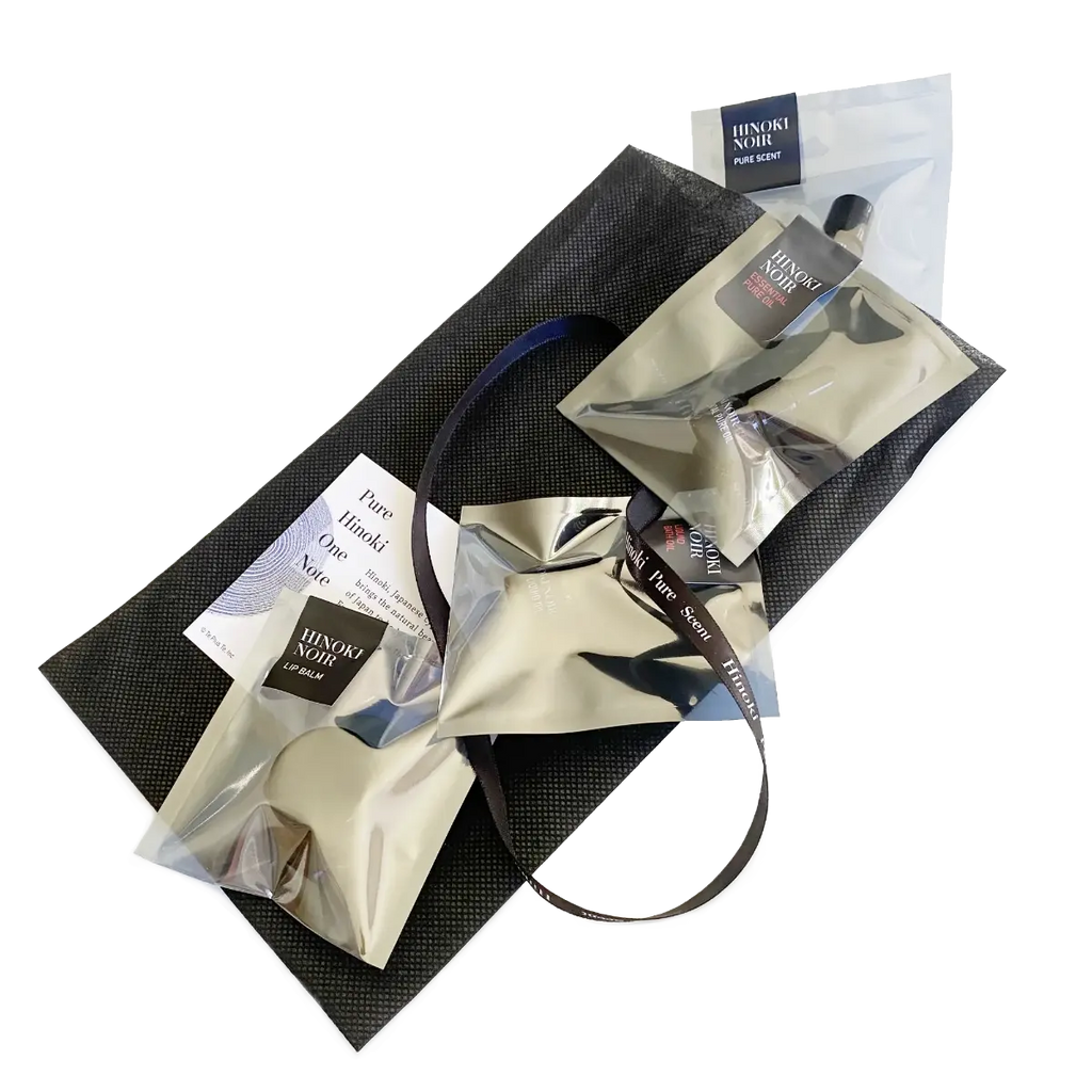 Hinoki Noir & Noir Red Discovery Set, four minis in labeled silver pouches on a black gift bag with ribbon — TE PLUS TE