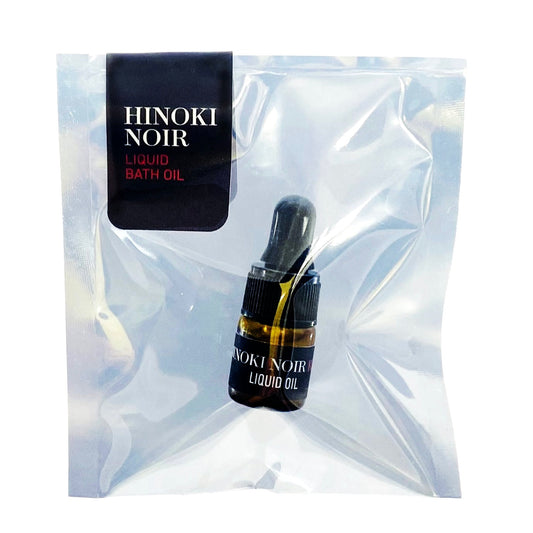 Hinoki Noir liquid bath oil bottle with packaging on a white background