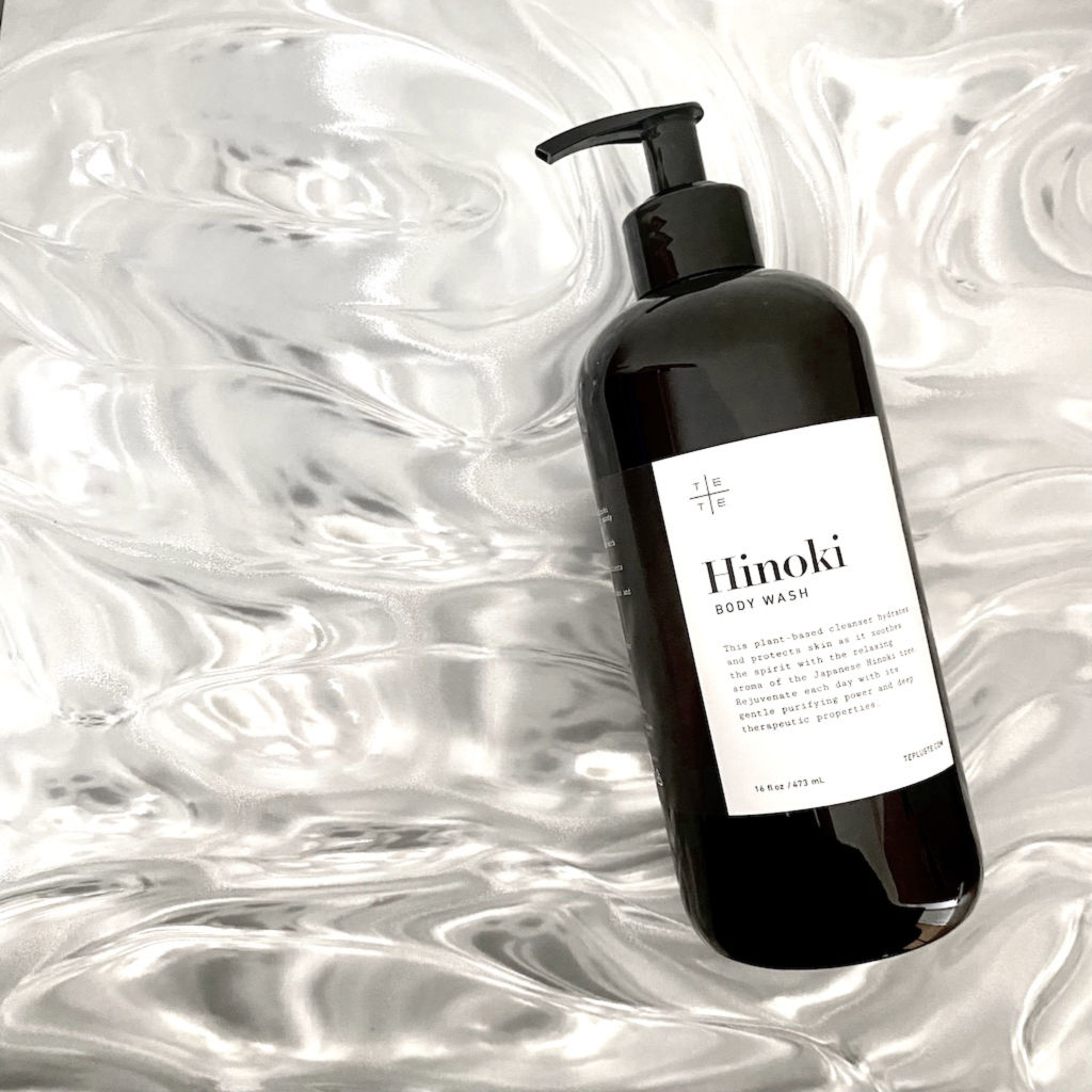 Black bottle of Hinoki body wash on a textured white background -TE PLUS TE