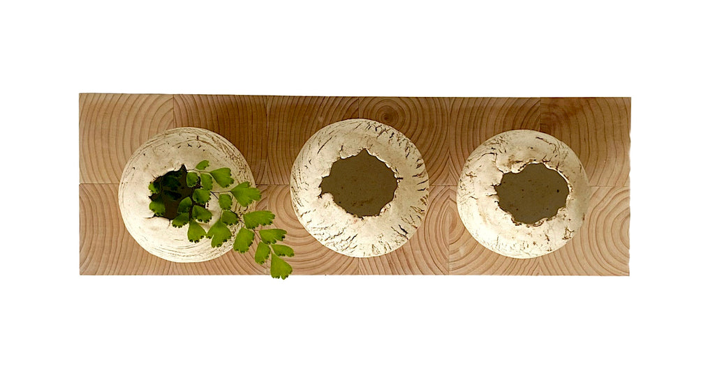 Three circular ceramic vases with different textures on a wooden surface