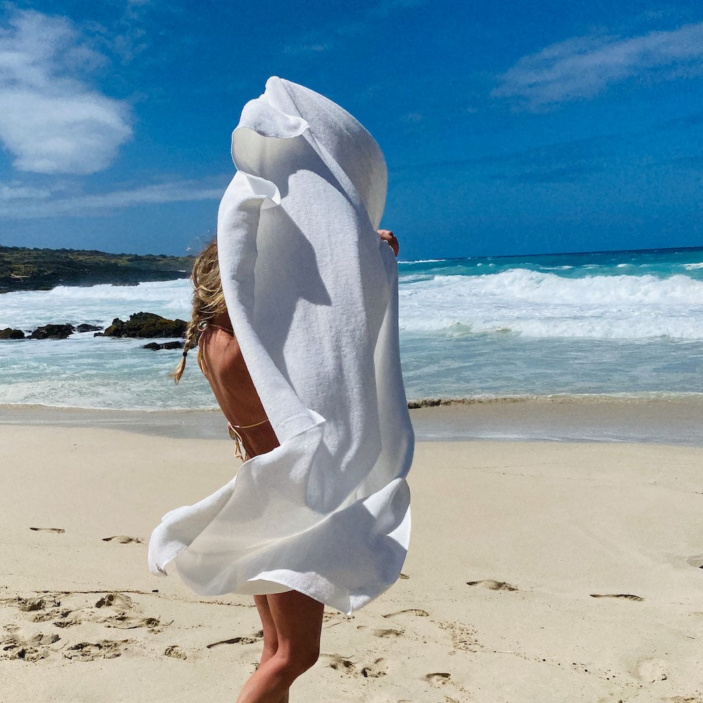 A large natural white Japanese super extra large towel waving against a clear blue sky  on the beach— TE PLUS TE