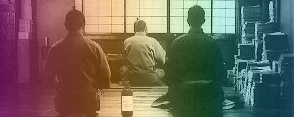 Three individuals in traditional attire sitting in a room with a bottle on a table.